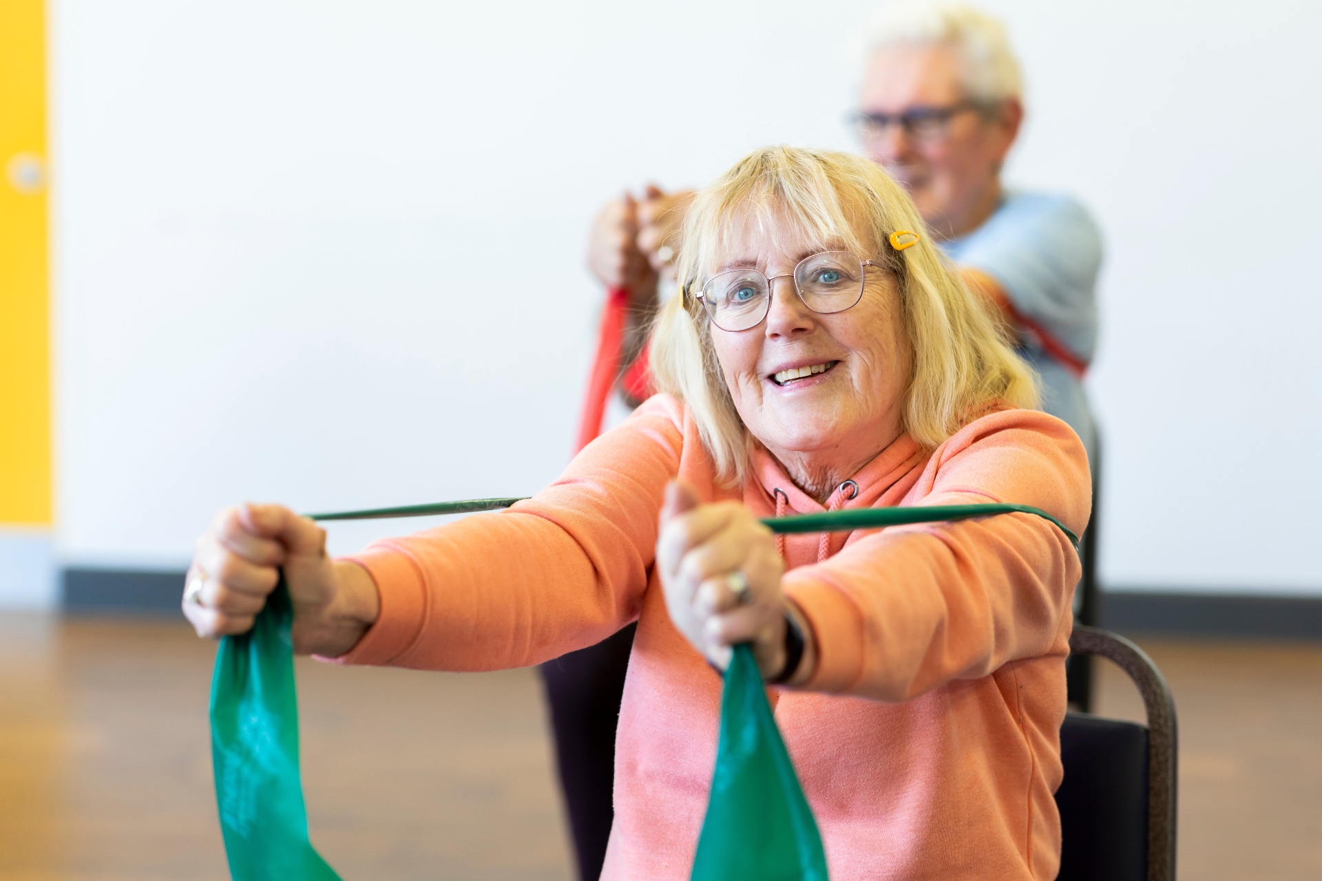 Older woman confidently climbing the stairs at home holding the handrail, with a physiotherapist supporting close behind